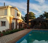 Vista de norte a sur desde la piscina a la casa y quincho al atardecer