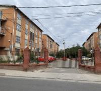  Fotografía del acceso principal del condominio, con entrada vehicular amplia, portón metálico y muros perimetrales de ladrillo que aportan seguridad y privacidad.