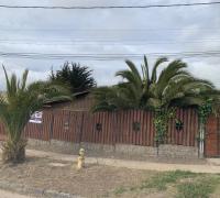 “Frontis de un terreno con dos casas, cercado con un portón corredero de madera y metal.