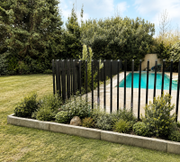Jardín amplio, piscina cercada y vegetación madura alrededor.