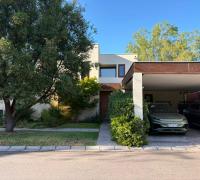 Fachada de casa de dos pisos con antejardín, acceso peatonal y estacionamientos exteriores.