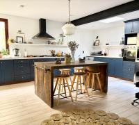 Amplia cocina equipada con isla central, muebles azules y lucarna de iluminación natural.