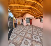 Acceso techado de la casa, con piso de baldosas y estructura de madera.