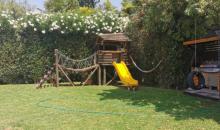 Jardín con árboles grandes y juegos para niños