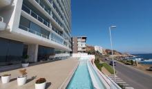 Linda piscina exterior con terraza y vista al mar