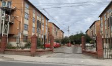  Fotografía del acceso principal del condominio, con entrada vehicular amplia, portón metálico y muros perimetrales de ladrillo que aportan seguridad y privacidad.