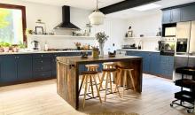 Amplia cocina equipada con isla central, muebles azules y lucarna de iluminación natural.
