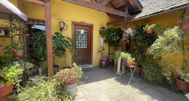 Entrada principal, puerta de madera y pequeña terraza; con ante jardín