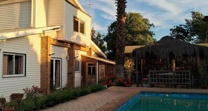 Vista de norte a sur desde la piscina a la casa y quincho al atardecer