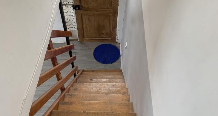 Vista desde el segundo nivel del departamento dúplex, donde se distribuyen tres dormitorios. La imagen muestra la escalera de madera sólida, que conecta ambos pisos y aporta calidez al interior..”