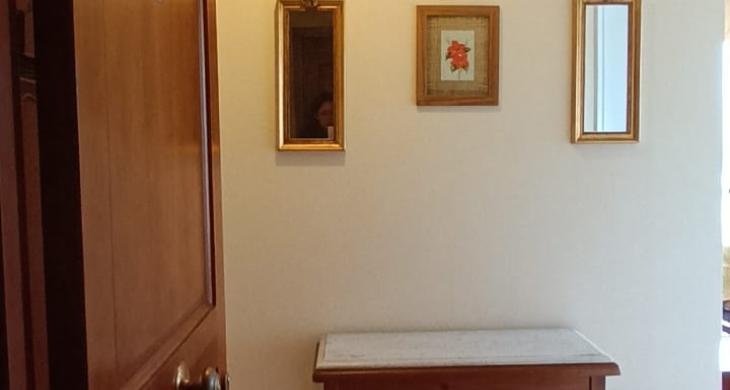 ACCESO PRINCIPAL CON MESA DE ARRIMO CON CUBIERTA DE MARMOL, PEQUEÑOS ESPEJOS EN MURO CON CUADRO DECORATIVOS