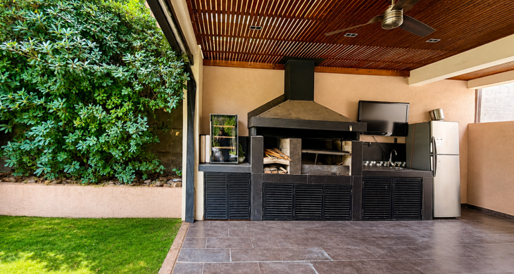 Quincho techado con parrilla, campana, lavaplatos, refrigerador y salida directa al jardín.