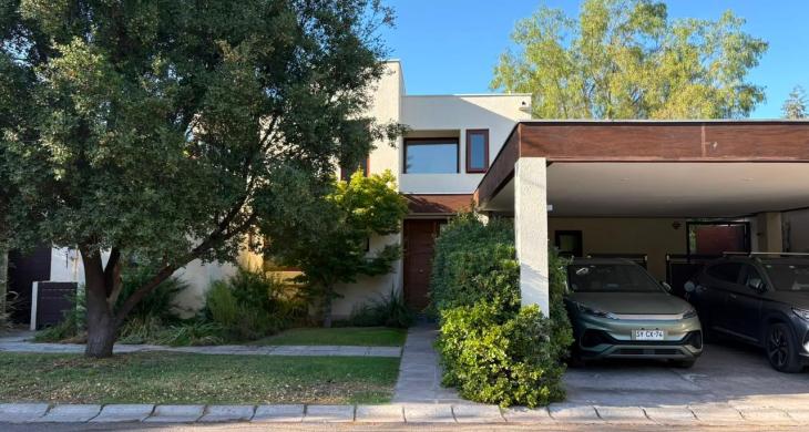 Fachada de casa de dos pisos con antejardín, acceso peatonal y estacionamientos exteriores.