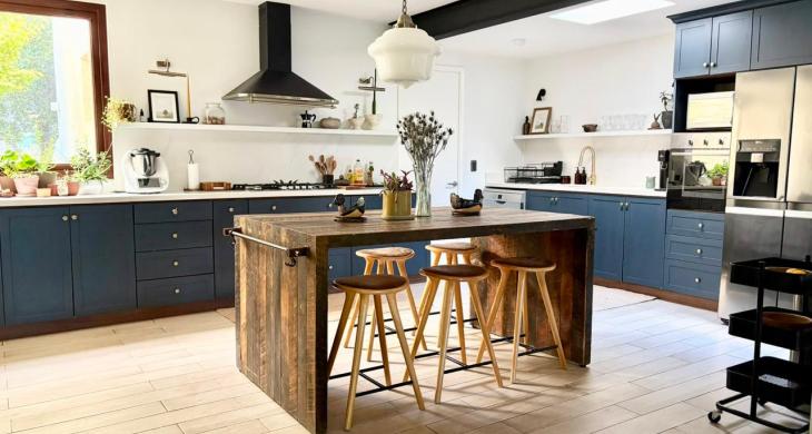 Amplia cocina equipada con isla central, muebles azules y lucarna de iluminación natural.
