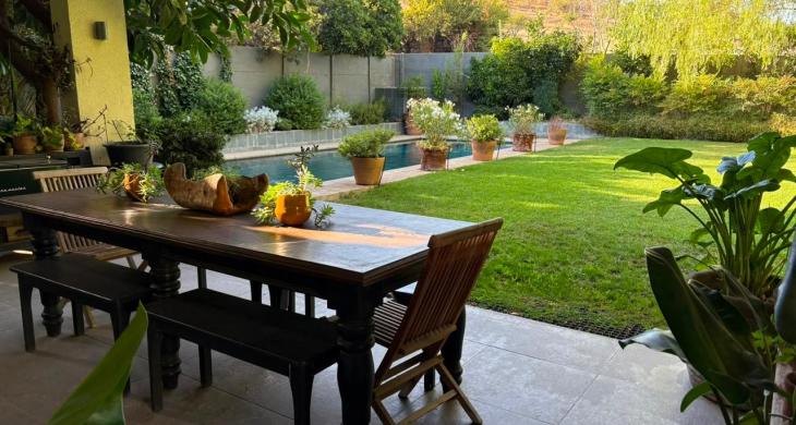 Terraza familiar techada conectada con el jardín y la piscina.
