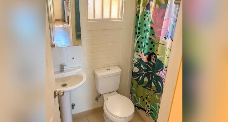 Vista de otro baño de la casa, con lavamanos, inodoro y ventana.