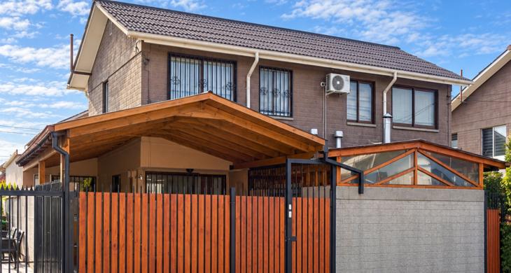 Fachada de casa de dos niveles en Rancagua, con cierre de madera y acceso techado.